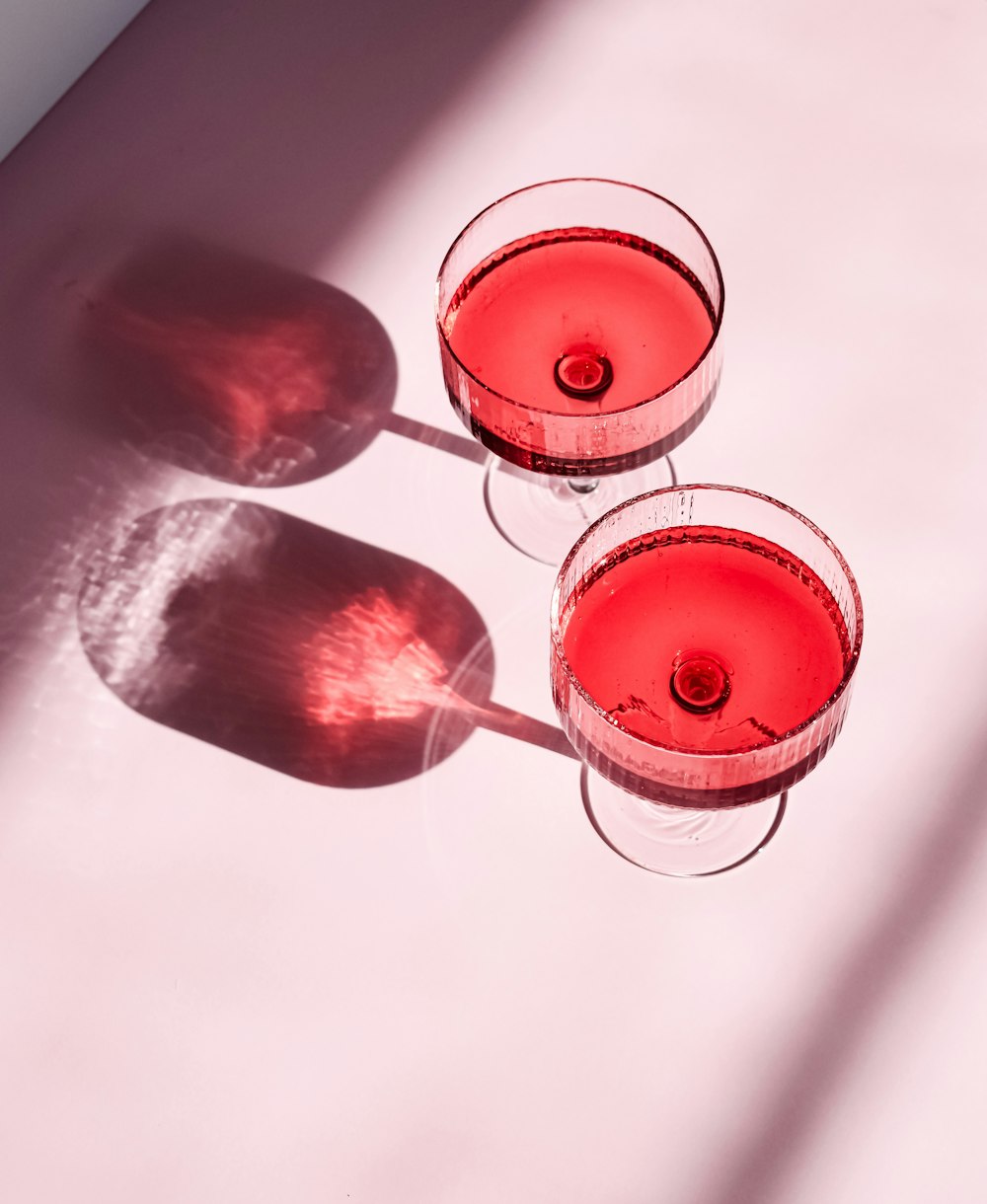 two glasses of red wine sitting on a table