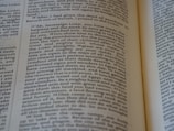 An open book with a close-up view of the text on its pages. The text is structured in paragraphs with justified alignment. It features a formal tone, possibly indicating a passage from a religious or historical context.
