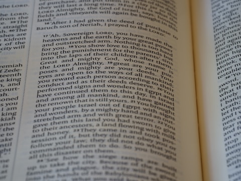 An open book with a close-up view of the text on its pages. The text is structured in paragraphs with justified alignment. It features a formal tone, possibly indicating a passage from a religious or historical context.