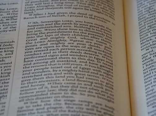 An open book with a close-up view of the text on its pages. The text is structured in paragraphs with justified alignment. It features a formal tone, possibly indicating a passage from a religious or historical context.