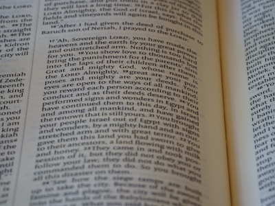 An open book with a close-up view of the text on its pages. The text is structured in paragraphs with justified alignment. It features a formal tone, possibly indicating a passage from a religious or historical context.