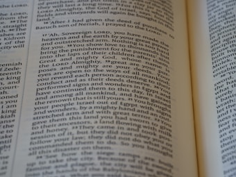 An open book with a close-up view of the text on its pages. The text is structured in paragraphs with justified alignment. It features a formal tone, possibly indicating a passage from a religious or historical context.