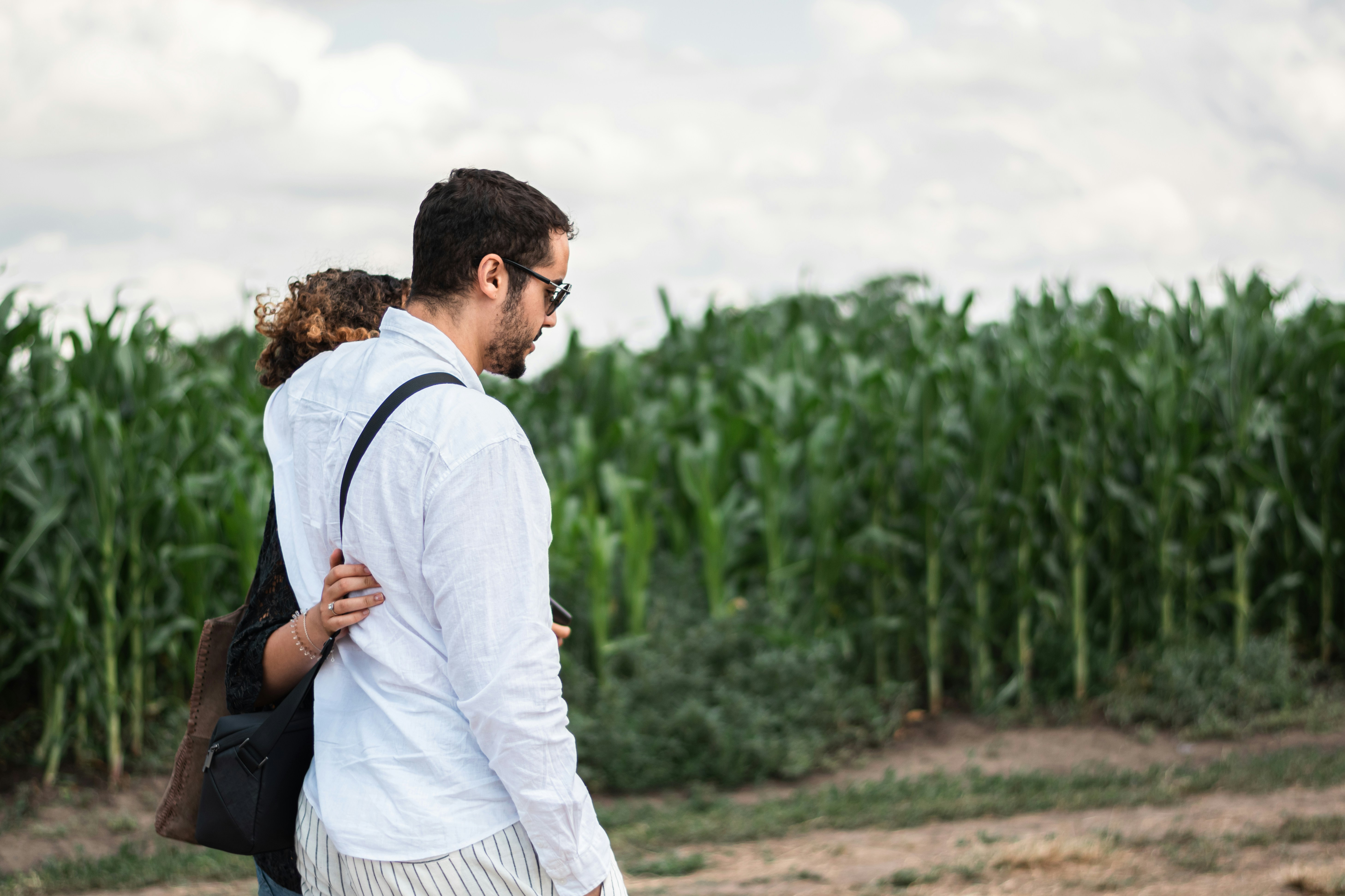 a man and a woman walking through a corn field