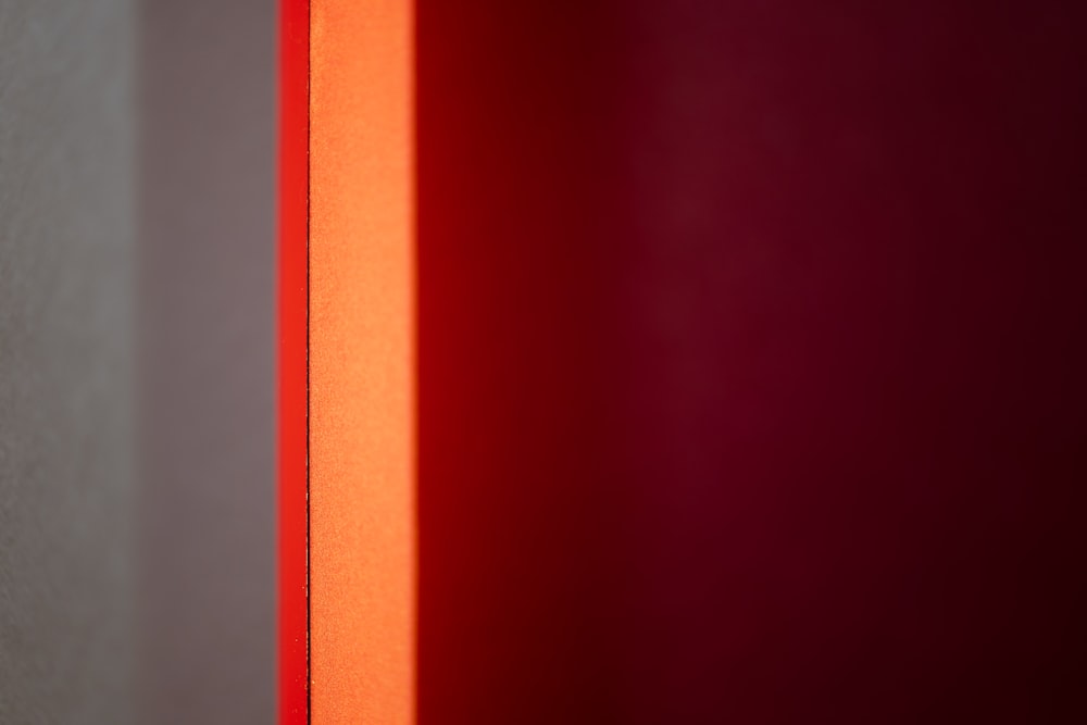 une lumière rouge qui brille à travers une fenêtre dans une pièce