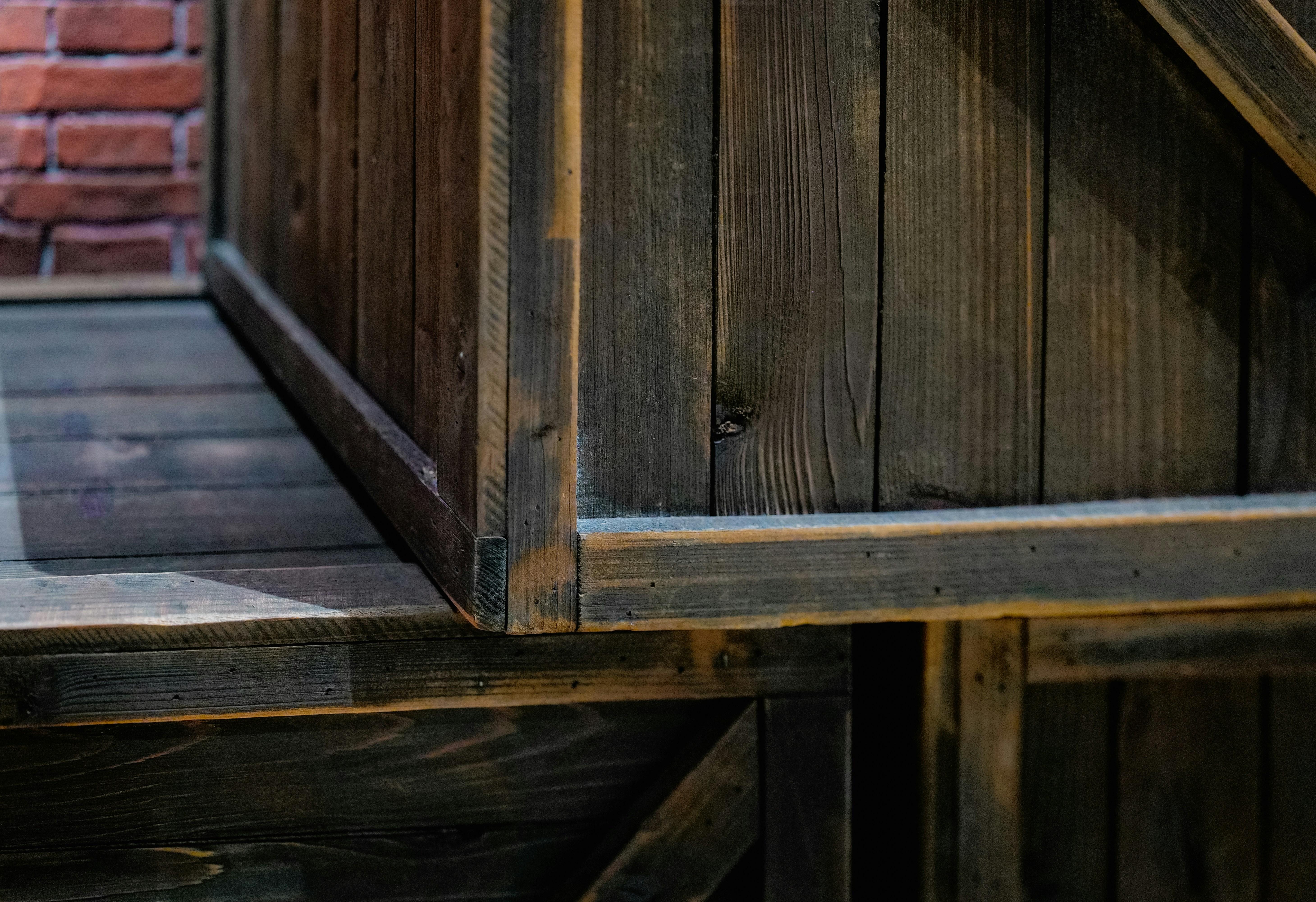 a close up of a wooden bench near a brick wall