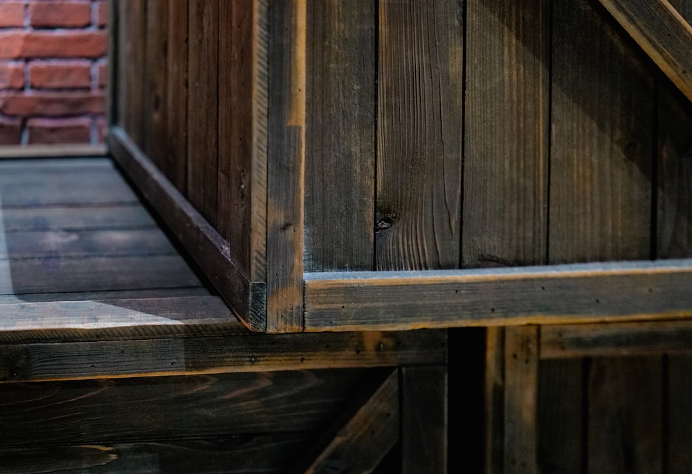 a close up of a wooden bench near a brick wall