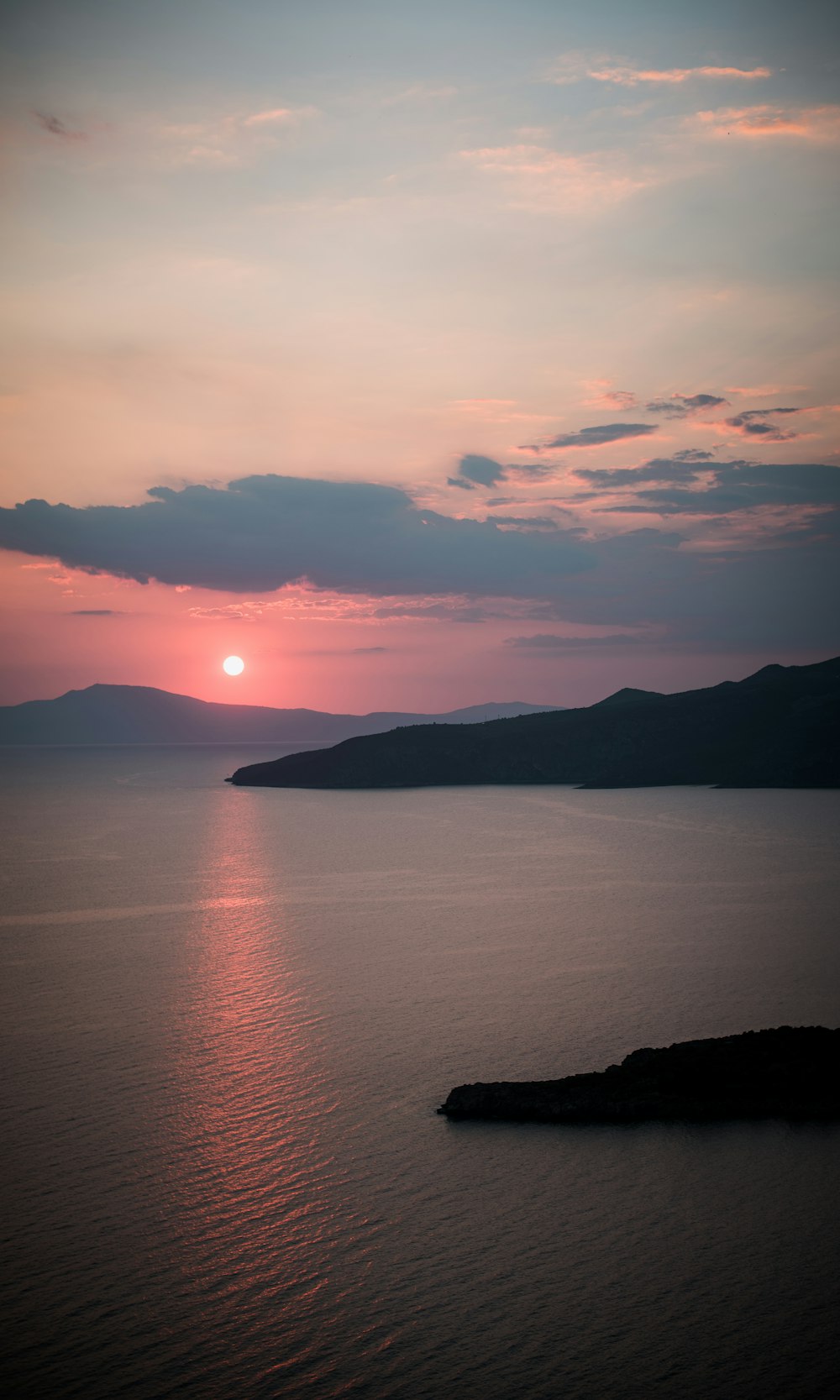 a large body of water with a sunset in the background