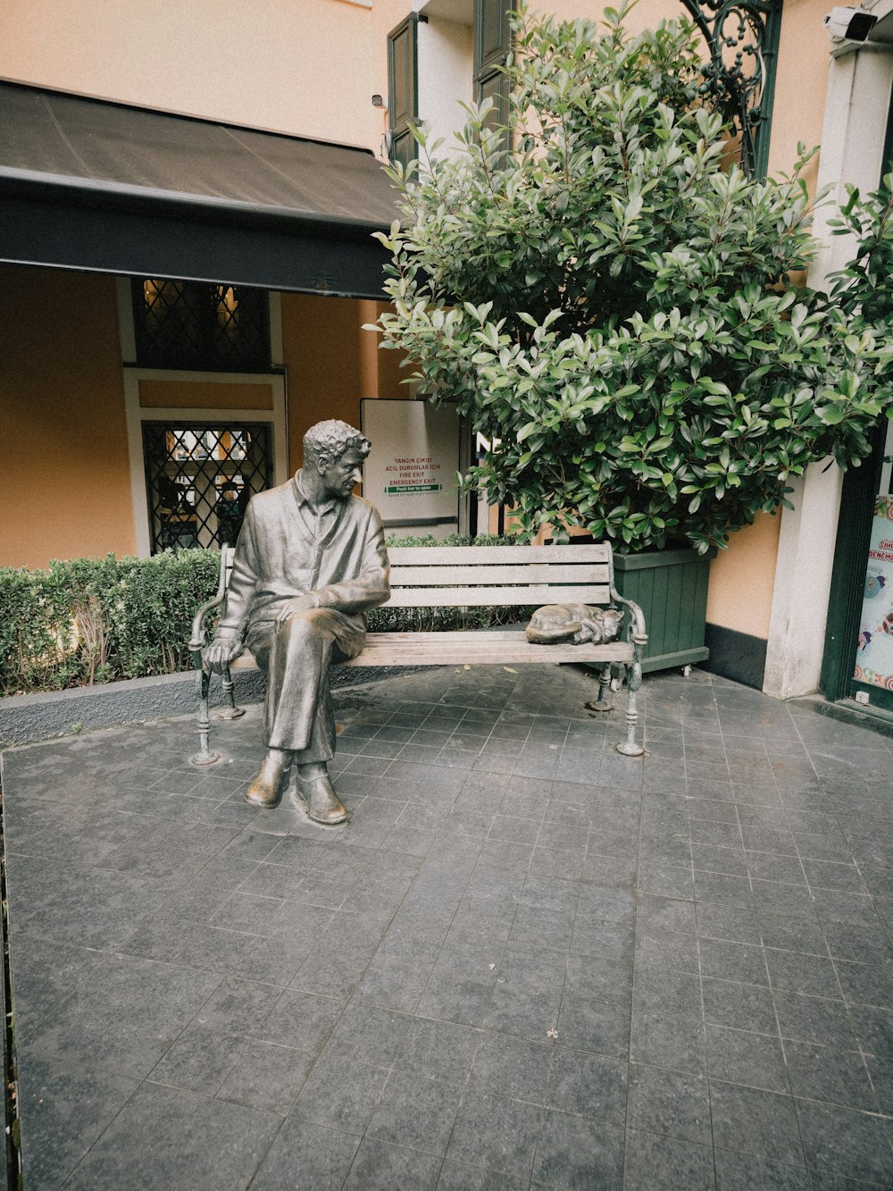Statue eines Mannes, der auf einer Bank sitzt