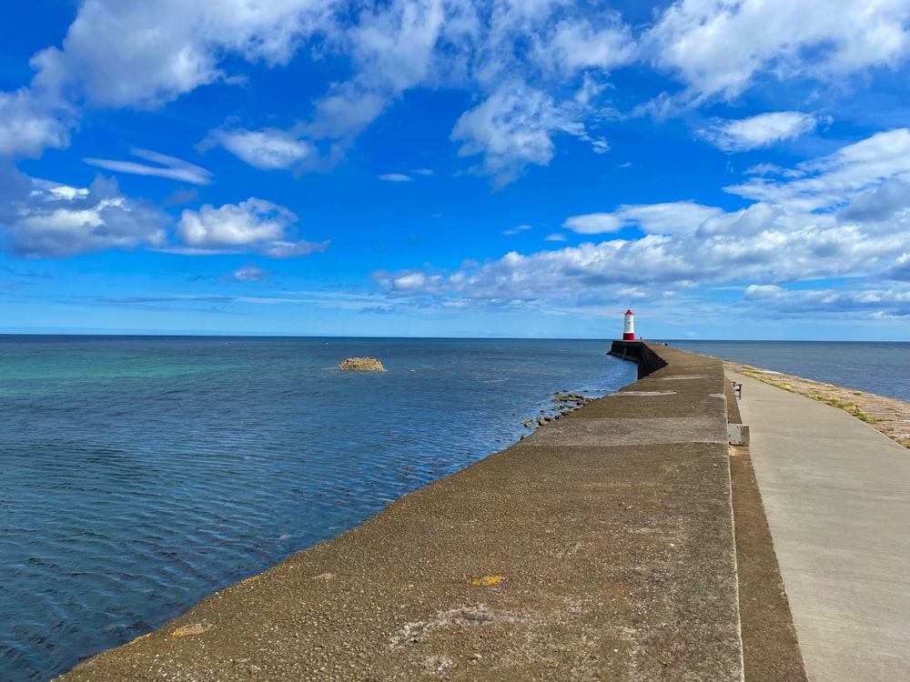 a long pier with a light house in the distance