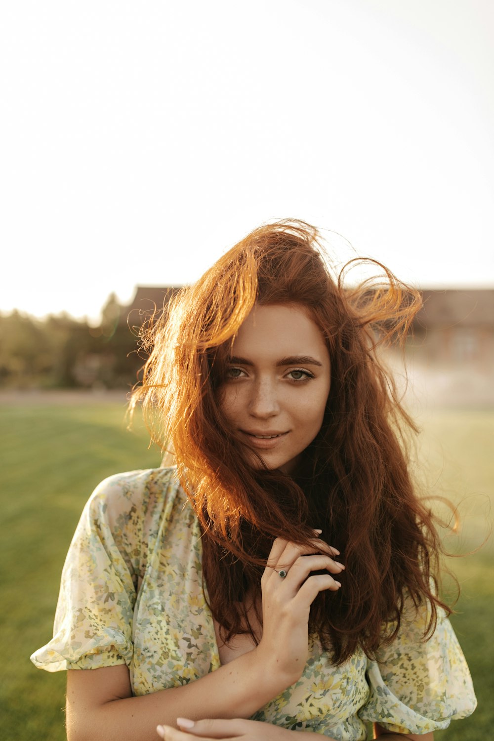 a woman with long red hair standing in a field