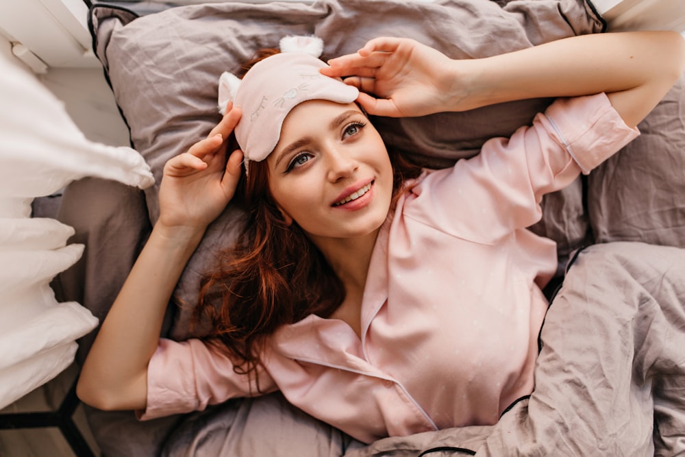 uma mulher deitada em cima de uma cama ao lado de um travesseiro