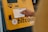 A hand interacts with a touchscreen on a Bitcoin ATM, which is yellow and prominently displays a Bitcoin logo. The screen shows options related to purchasing cryptocurrency.
