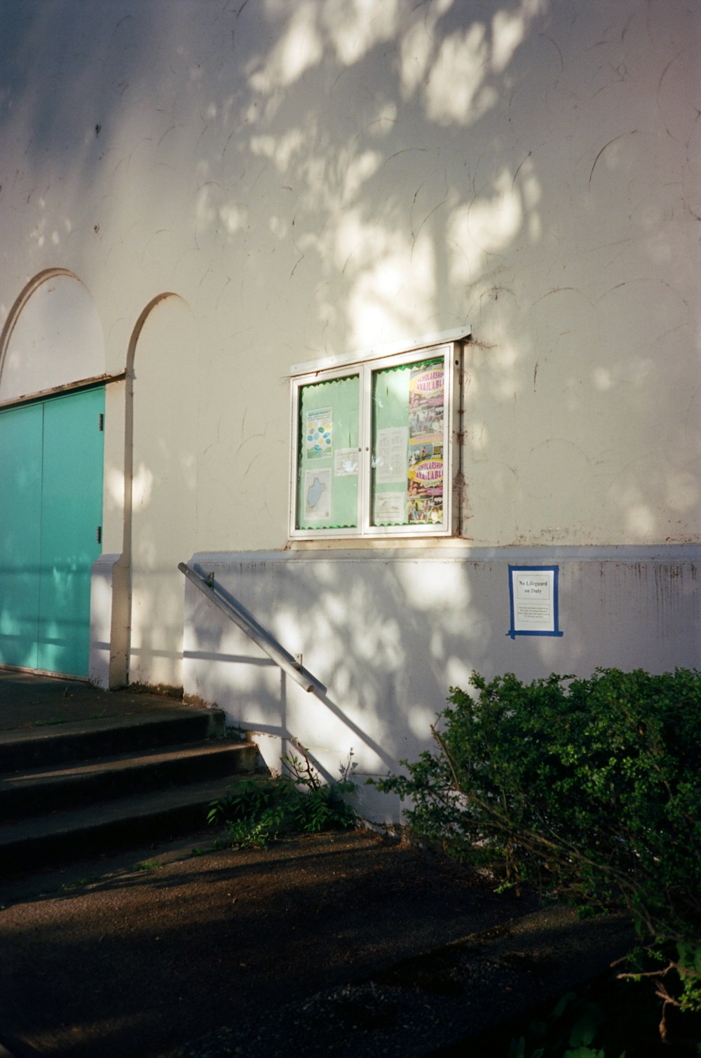 a white building with a blue door and a green door