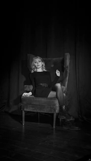 Powerful businesswoman seated confidently at a sleek desk, illuminated by soft, mysterious lighting.
