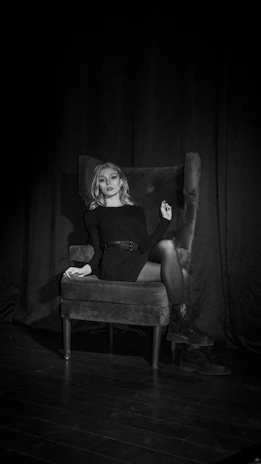 Powerful businesswoman seated confidently at a sleek desk, illuminated by soft, mysterious lighting.