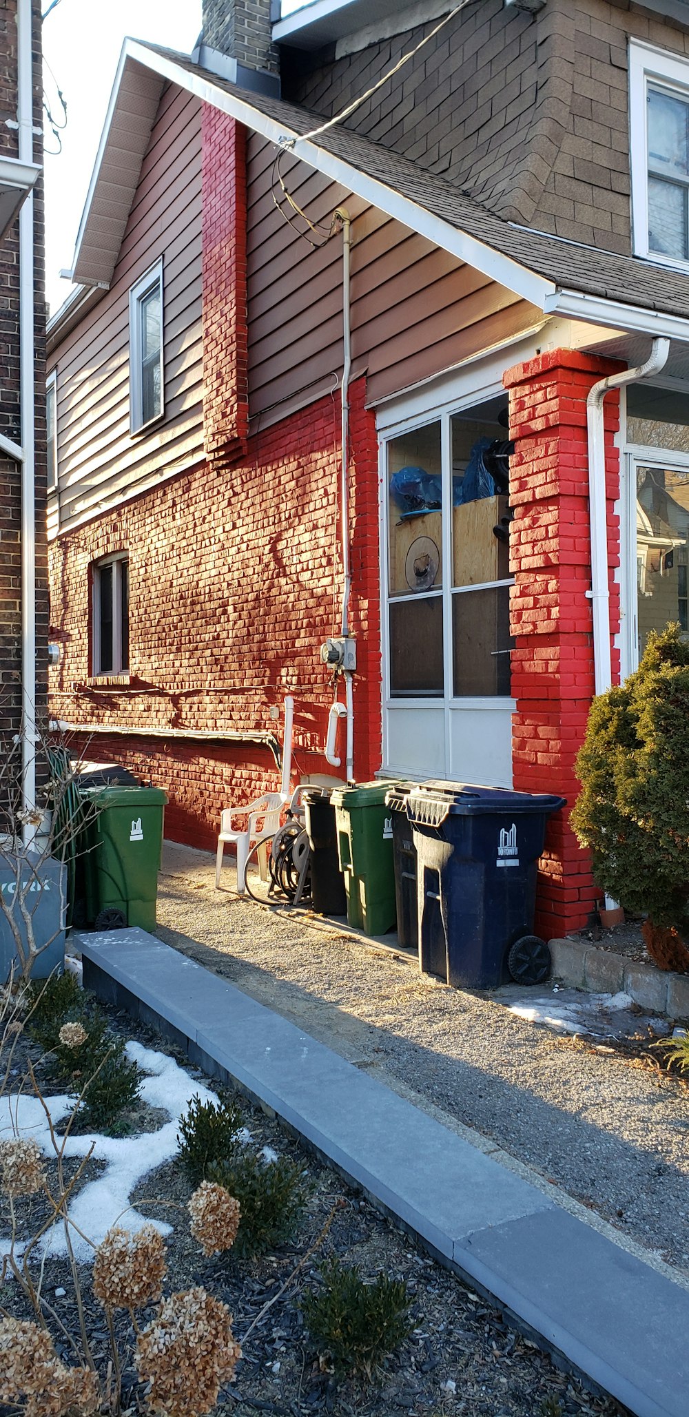 a red brick house with trash cans outside