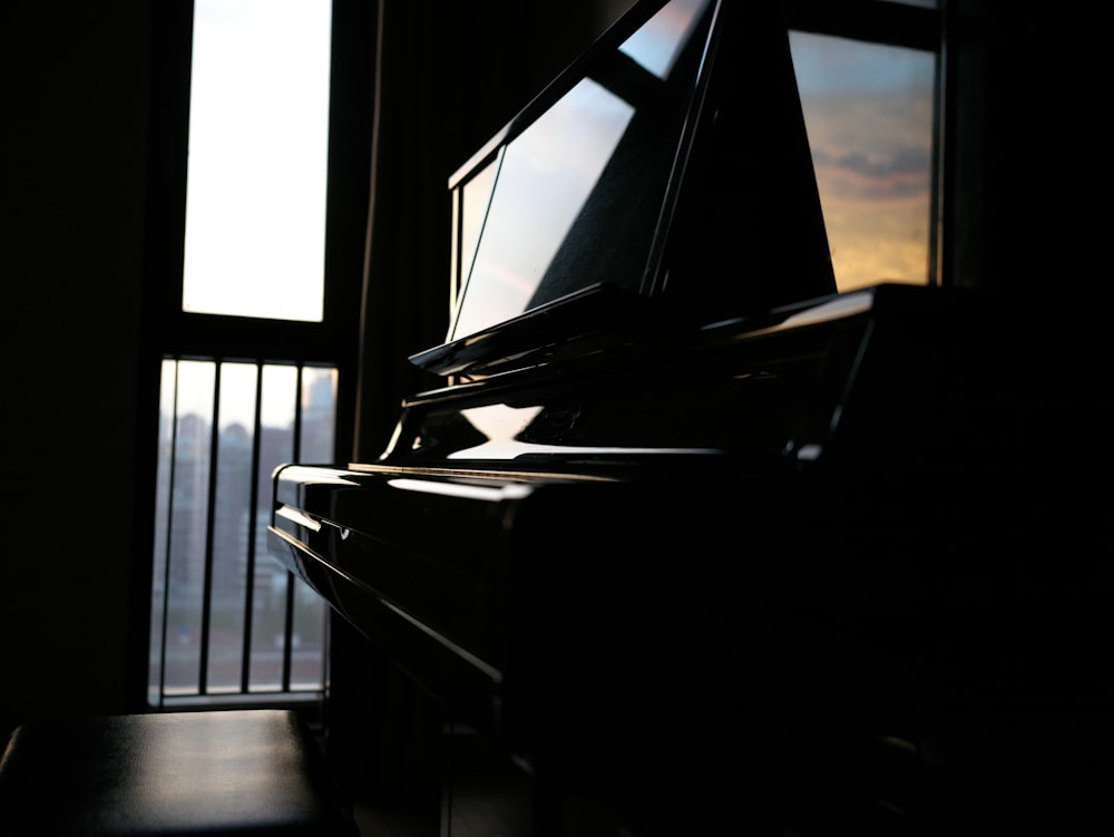 a piano sitting in front of a window in a dark room