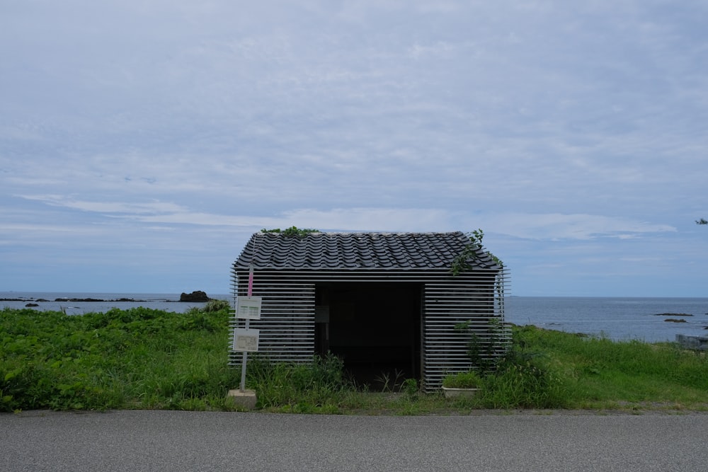 a small shed sitting on the side of a road next to the ocean