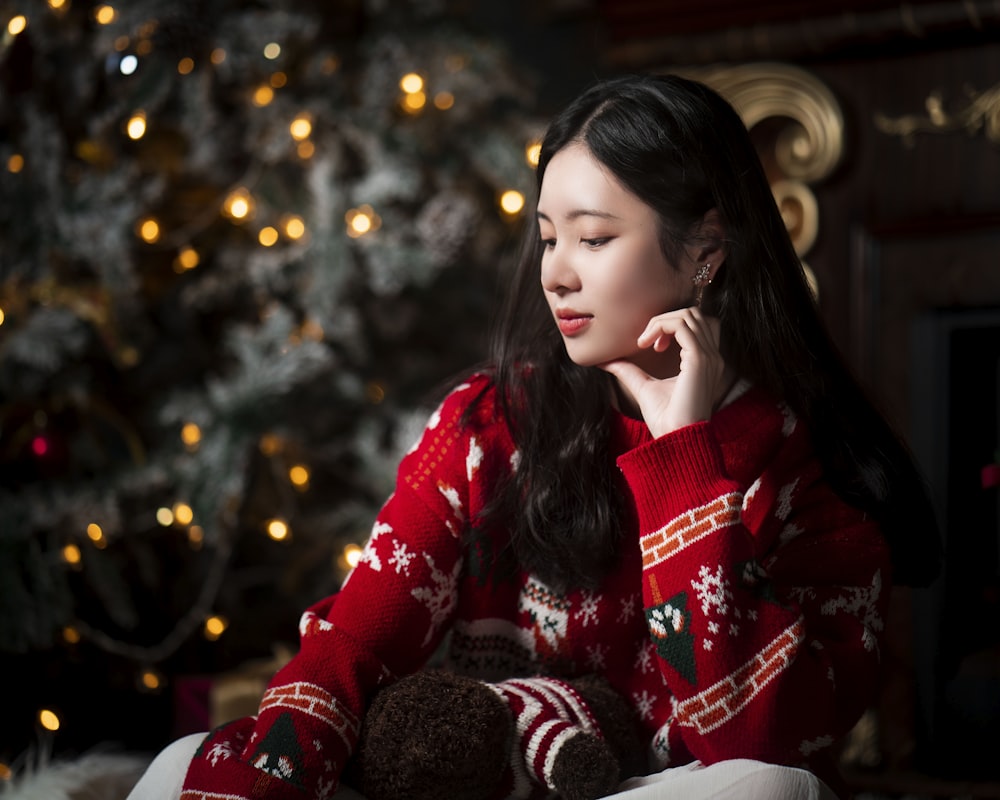 a woman sitting in front of a christmas tree talking on a cell phone