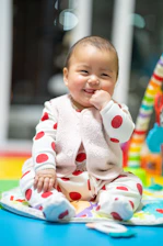A smiling baby playing with colorful sensory toys in a cozy classroom.