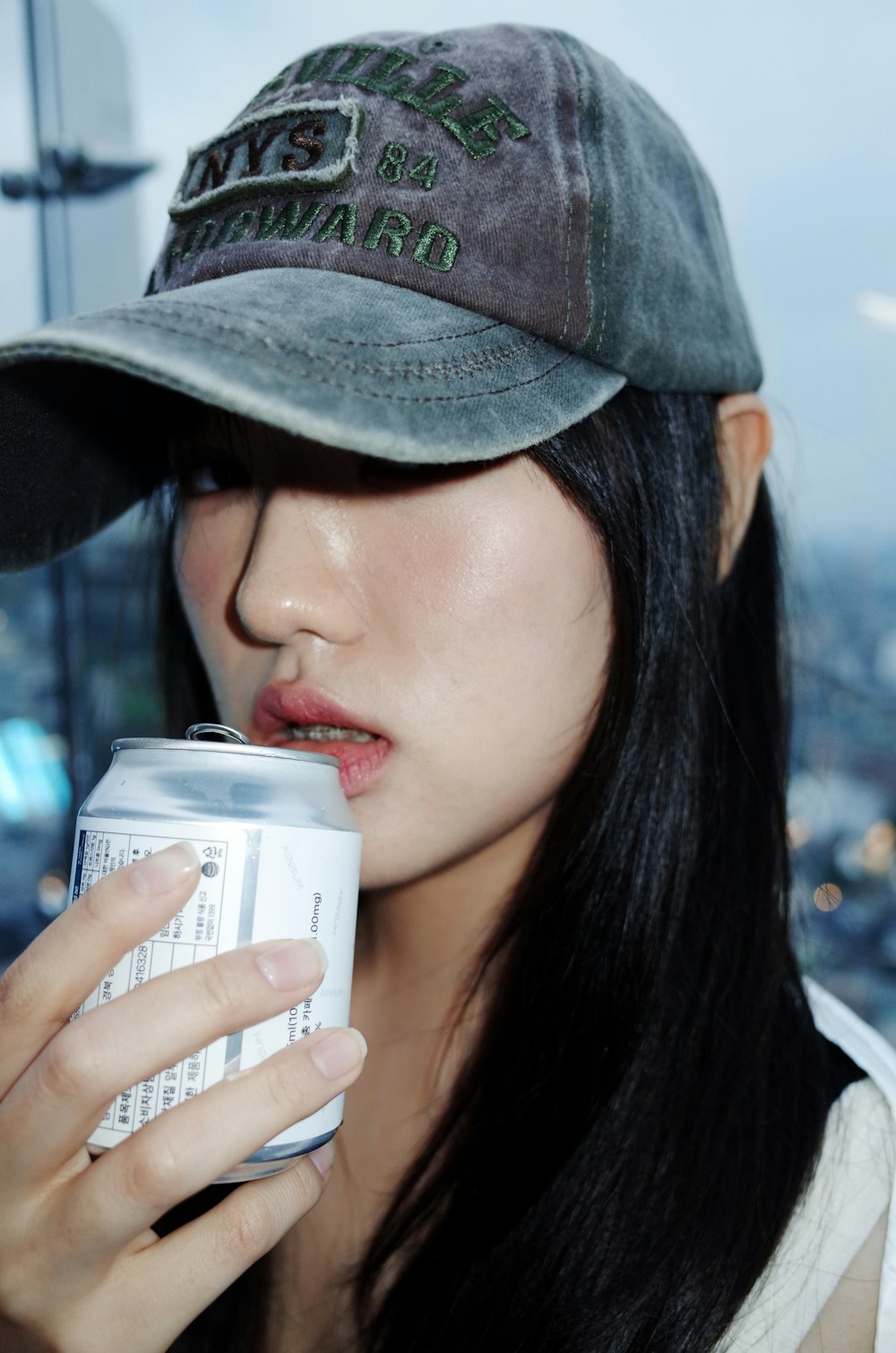 a woman wearing a hat drinking a can of beer