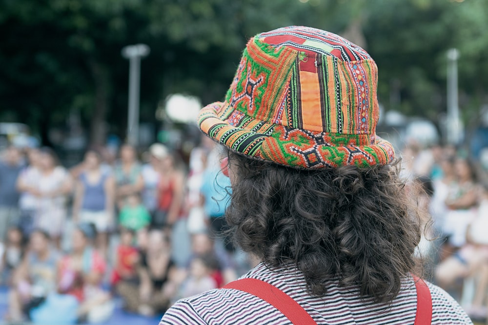 a person wearing a colorful hat with a crowd of people in the background