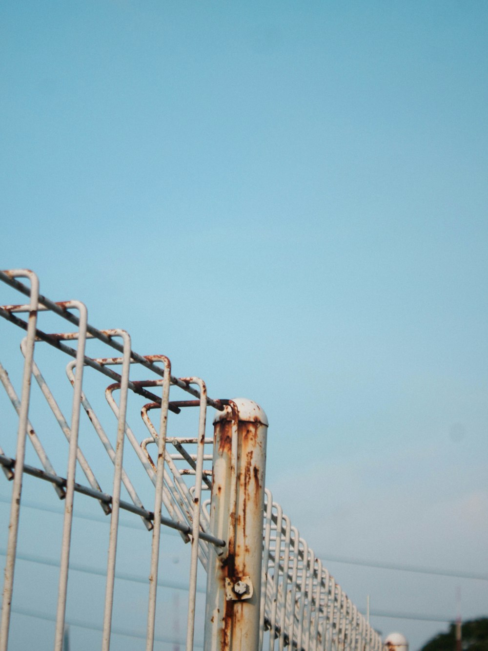a metal fence with a blue sky in the background
