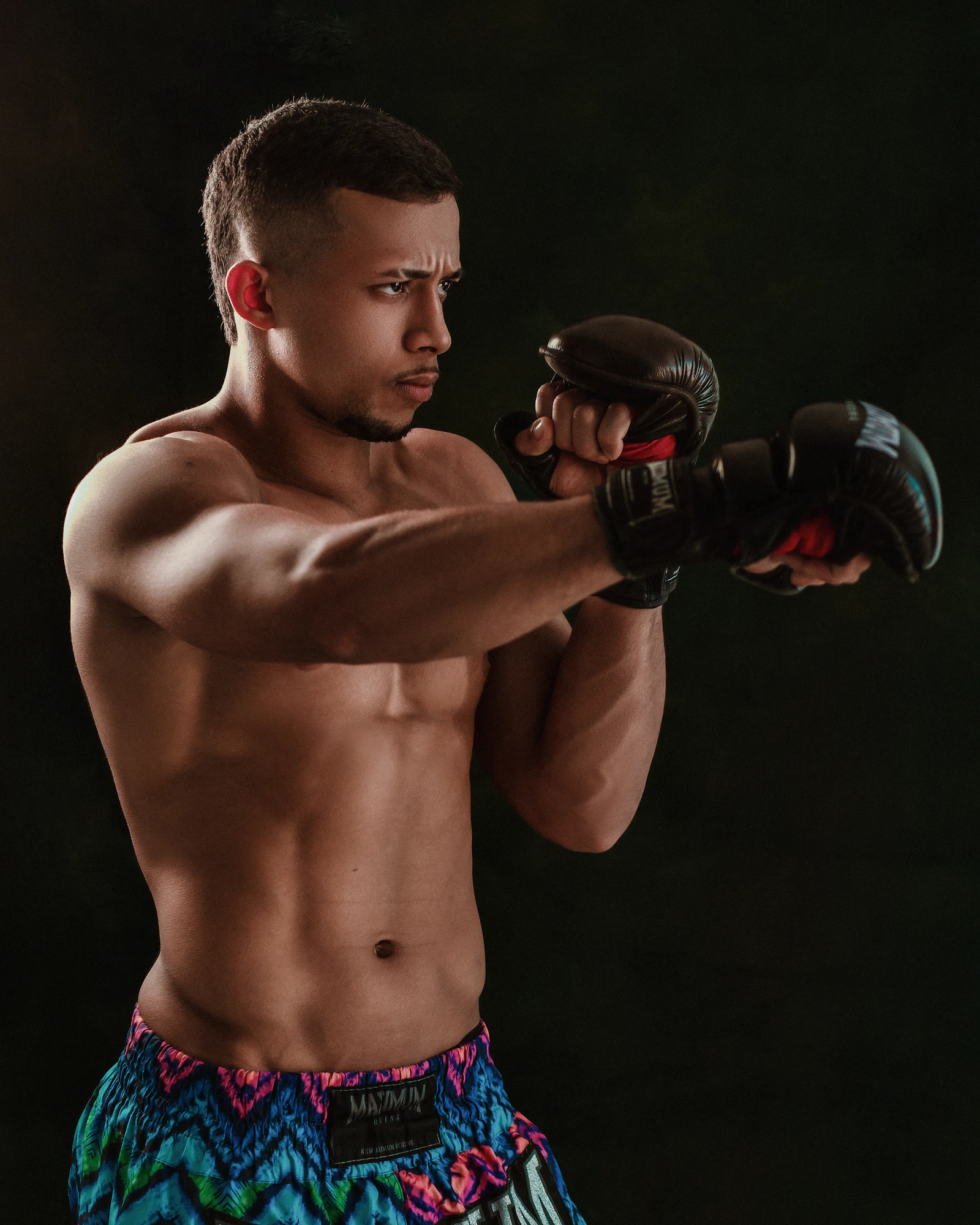 Male fighter in gloves training beside an MMA cage