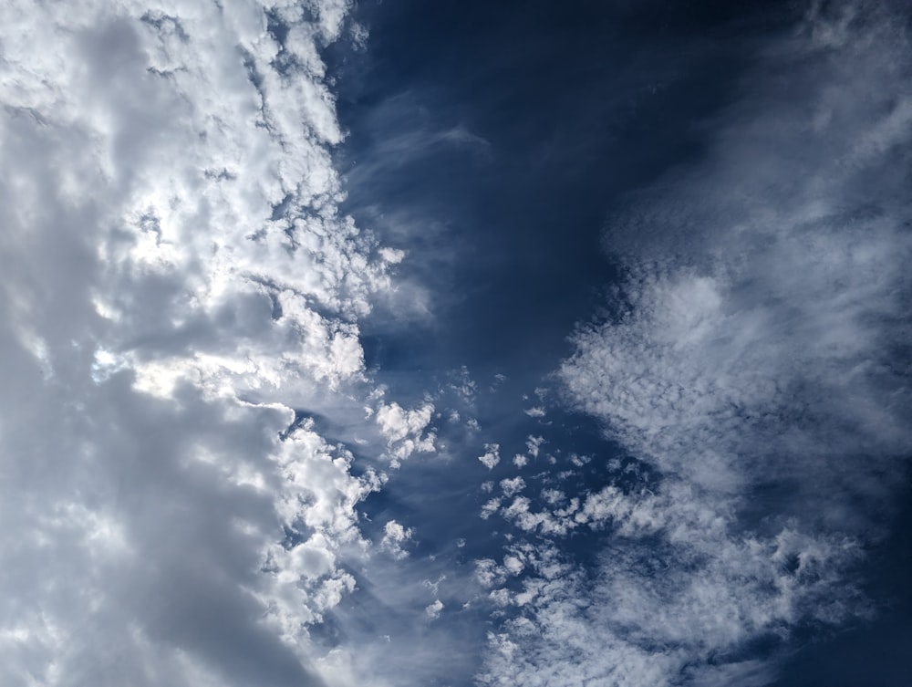 a plane flying through a cloudy blue sky