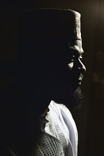 An elegant still capturing slender fingers adjusting a cowboy hat, framed by deep earthy tones and soft natural light.