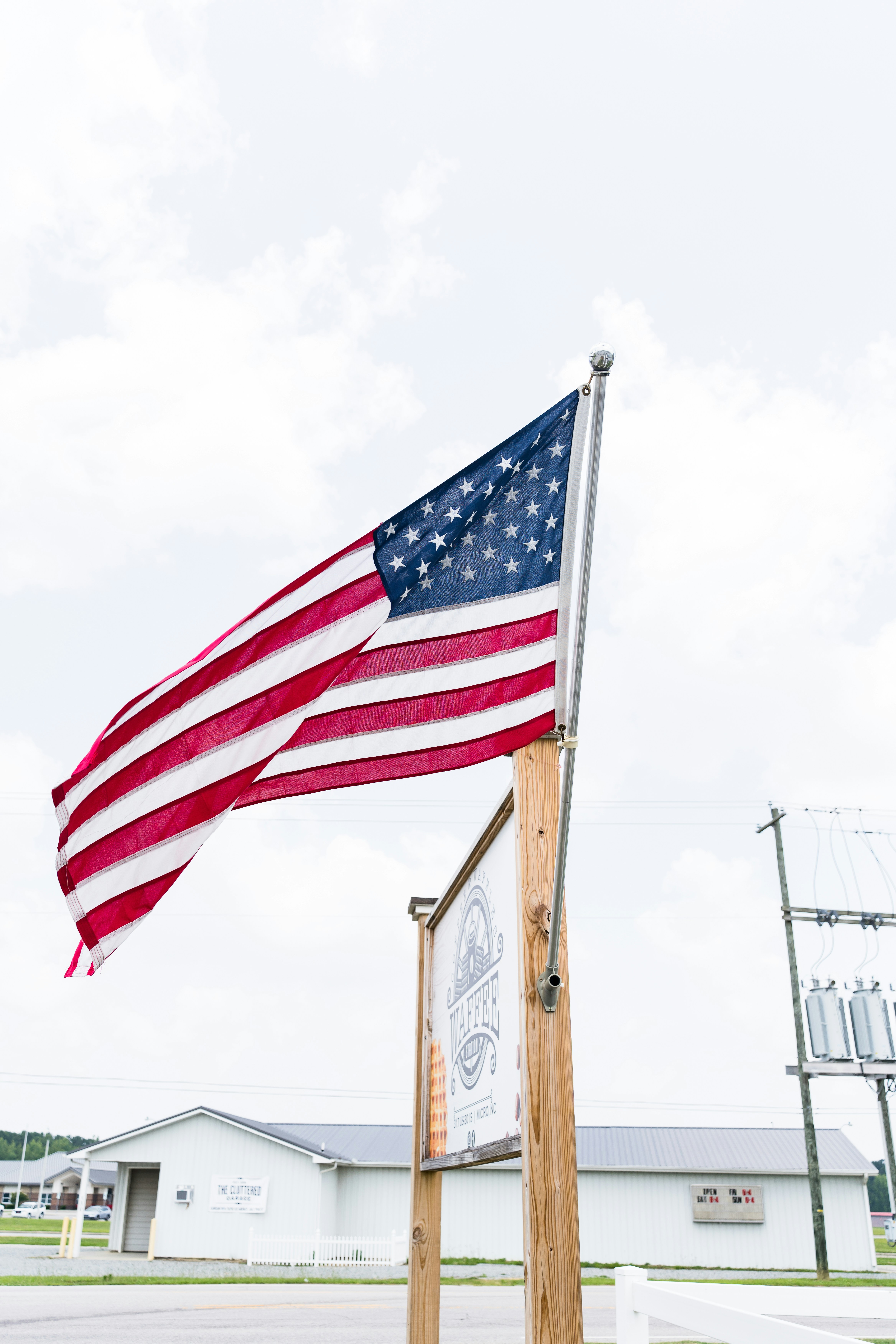 an american flag flying over a sign in front of a building