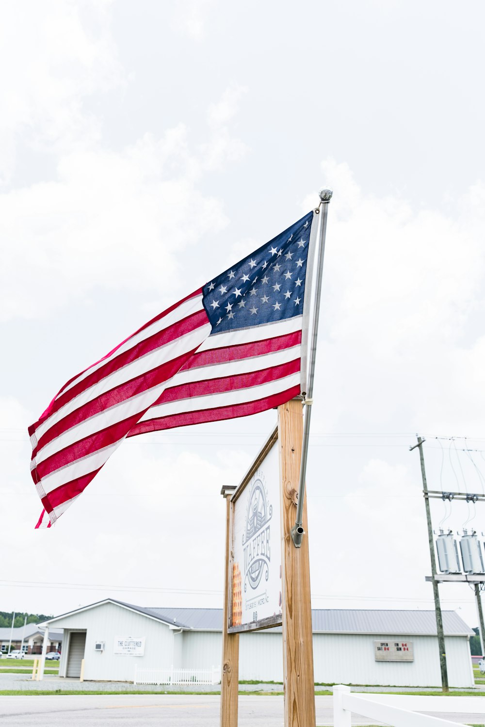 an american flag flying over a sign in front of a building