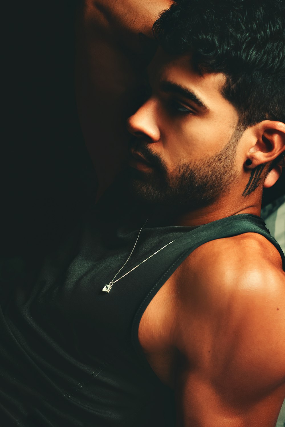 a man in a tank top is leaning against a wall