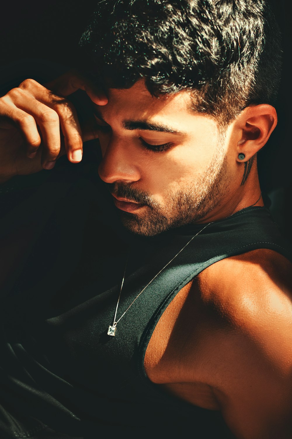 a man in a tank top holding his hand to his ear