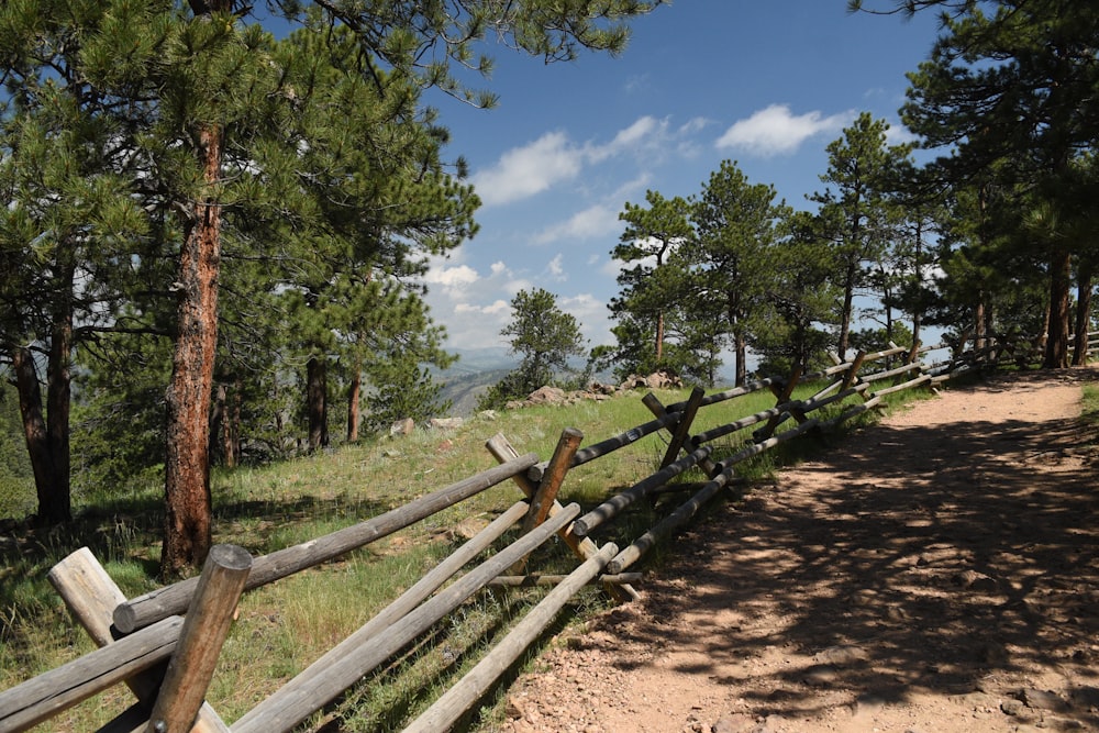 a wooden fence on the side of a dirt road