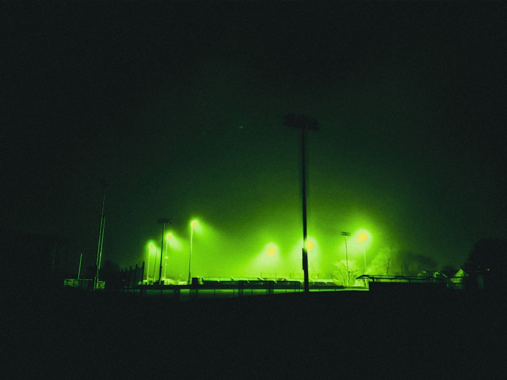 a row of green street lights on a dark street