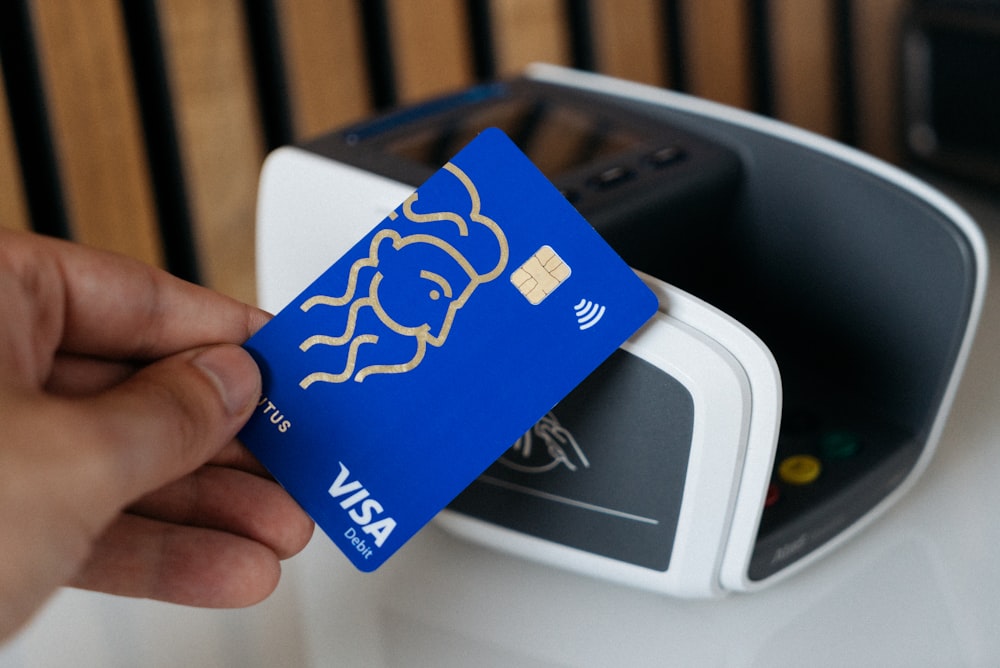 a person is holding a blue credit card