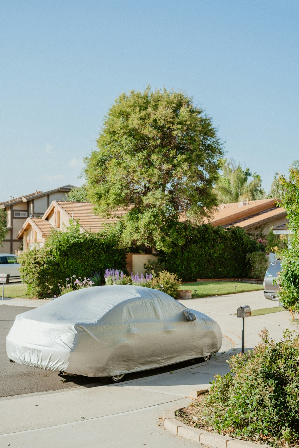 a car covered in a white tarp parked on the side of the road