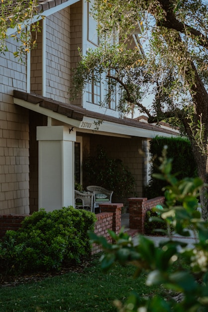 the front of a house with a large tree in front of it