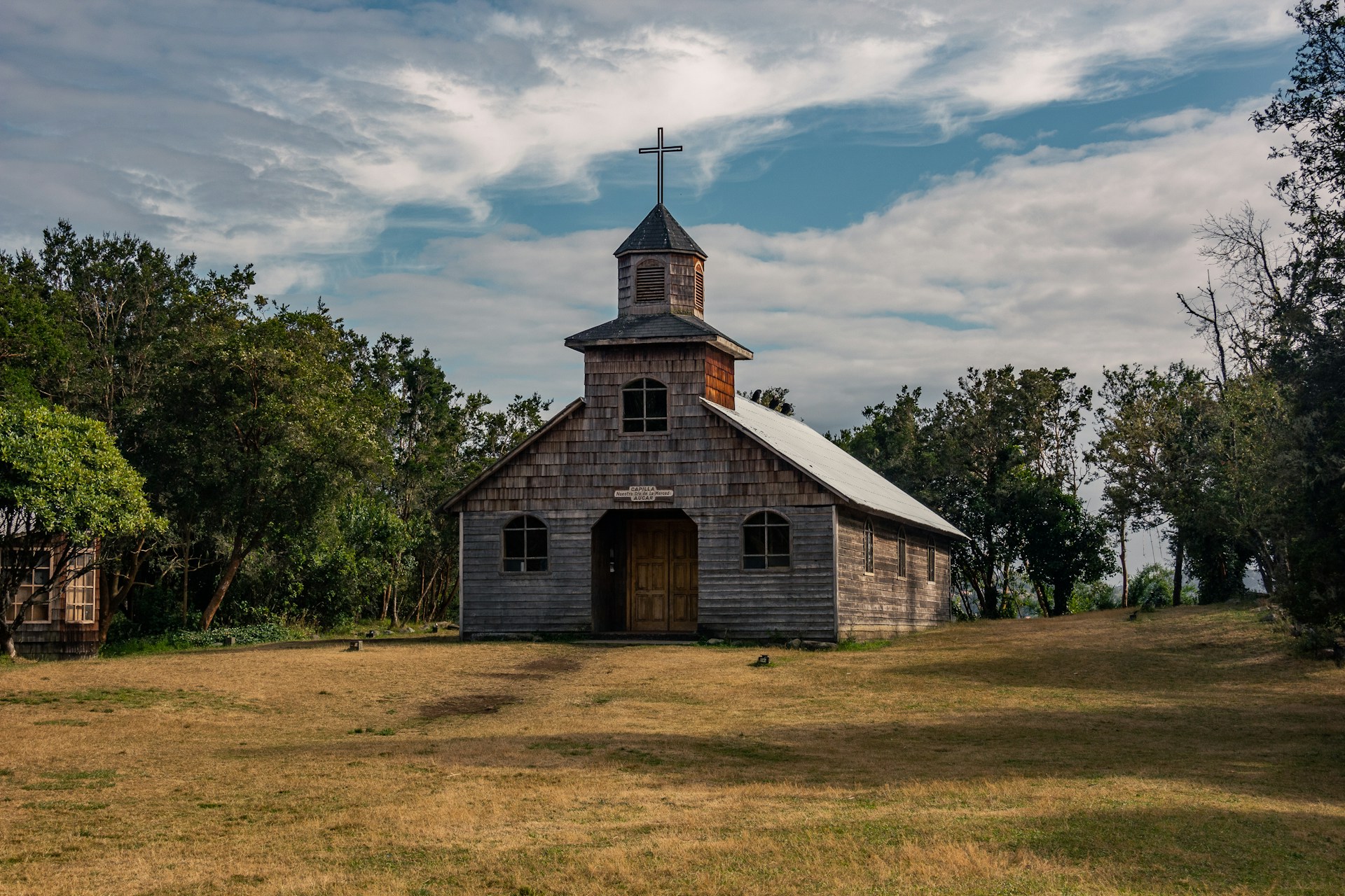 an old wooden church with a steeple and a cross on top