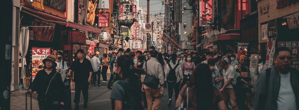 a group of people walking down a street next to tall buildings