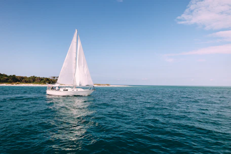 Traditional boat sailing near lush tropical islands under a bright blue sky.