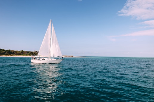 A sailboat gliding near the famous Arch of Cabo San Lucas under a clear blue sky.