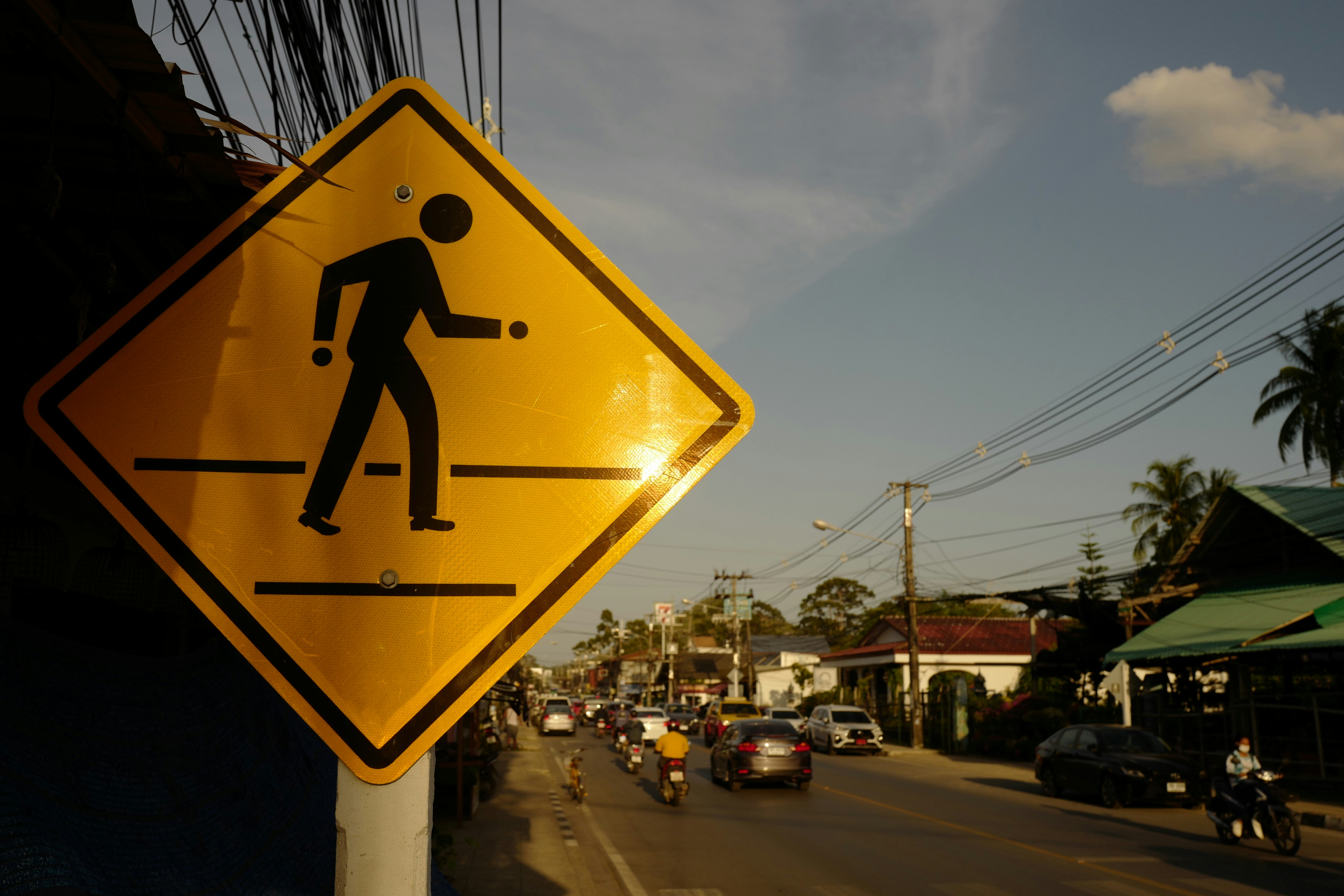 a yellow pedestrian crossing sign sitting on the side of a road