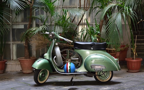 a green scooter parked in front of potted plants