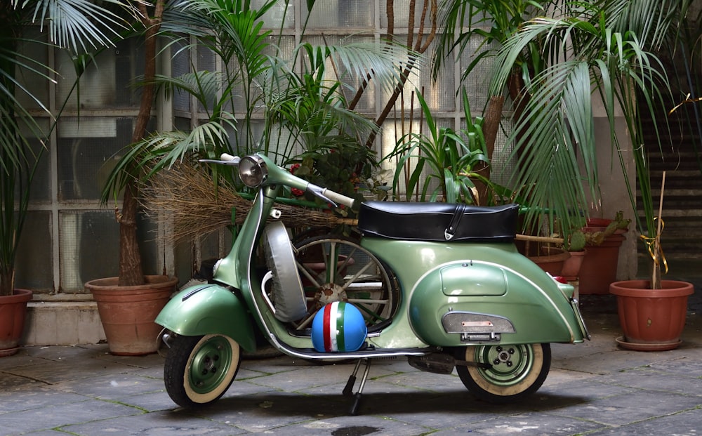 a green scooter parked in front of potted plants