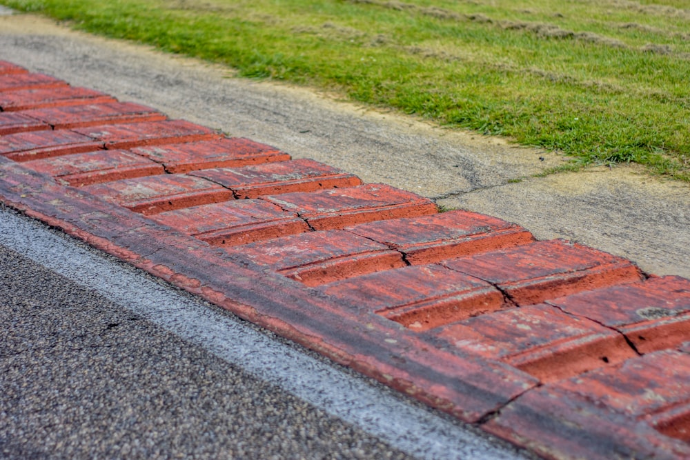 a close up of a brick road with grass in the background