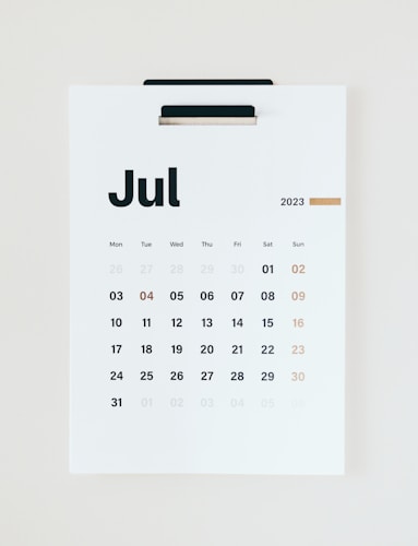A minimalist wall calendar for July 2023 featuring bold black numerals on a clean white background. The days of the week are arranged in a standard grid format, and the font used is modern and sans-serif. A thin strip of gold accent adds a touch of elegance.