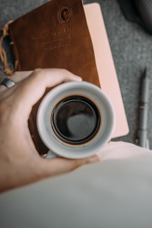 Close-up of hands typing on a keyboard with a notebook and coffee cup nearby.
