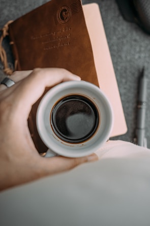 Close-up of handwritten notes and a cup of coffee on a wooden table.